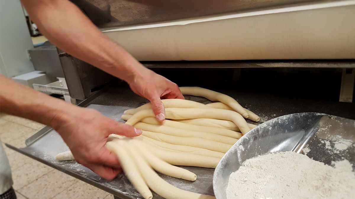 Bäcker nimmt Brezenstrang aus Maschine